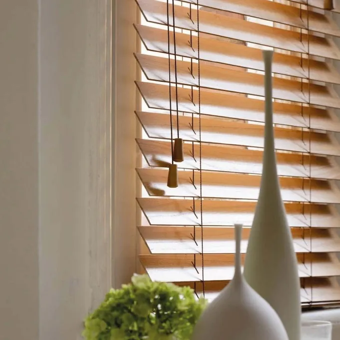 Wooden Venetian blind with tilted slats letting warm light into a room.